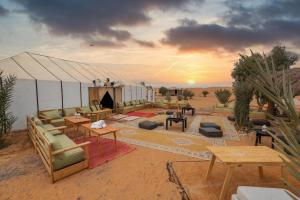 una tenda nel deserto con divani e tavoli di Golden Camp & Oasis a Merzouga