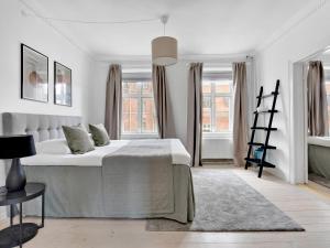 1 dormitorio blanco con 1 cama grande y ventanas en Sanders Stage - Charming Three-Bedroom Apartment Near Nyhavn, en Copenhague
