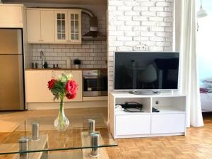 una sala de estar con TV y un jarrón de flores en Fabryczna, en Varsovia