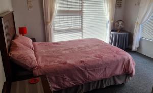 1 dormitorio con cama rosa y ventana en Kleinbegin, 3 bedroom homely house, en Gansbaai