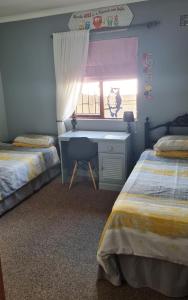 1 dormitorio con 2 camas, escritorio y ventana en Kleinbegin, 3 bedroom homely house, en Gansbaai
