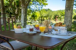 einen Tisch mit Frühstückszutaten und Getränken darauf in der Unterkunft Hôtel L'Hermitage in Pernes-les-Fontaines