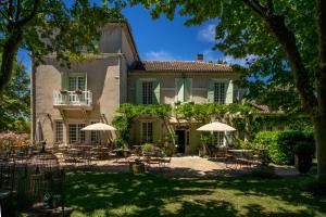 a house with chairs and umbrellas in front of it at Hôtel L'Hermitage in Pernes-les-Fontaines