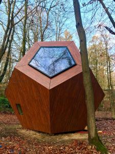a large wooden dog house with a window on a tree at Utopia Village - Art & Nature Lodges in Jurbise