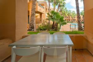 uma mesa de madeira e cadeiras numa varanda com palmeiras em Casa Felicidad em Los Alcázares