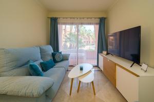 un soggiorno con divano blu e TV a schermo piatto di Casa Felicidad a Los Alcázares