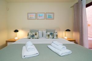 um quarto com uma cama com toalhas brancas em Casa Felicidad em Los Alcázares
