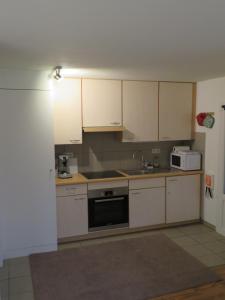 a kitchen with white cabinets and a sink and a microwave at Les Renardeaux in Malmedy