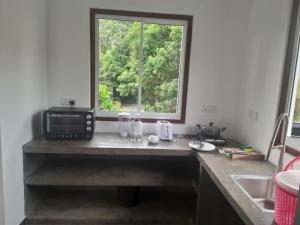 a kitchen counter with a microwave and a window at Hotel Paradiso, in Unawatuna