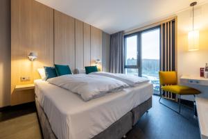 Cette chambre comprend un grand lit et une fenêtre. dans l'établissement Serways Hotel Hösel, à Ratingen