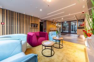 a living room with a blue couch and pink chairs at Serways Hotel Hösel in Ratingen