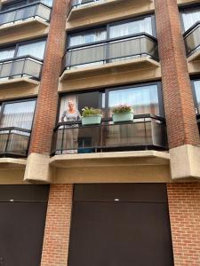 a man standing on a balcony of a building at Appart sympa 6p avec garage et terrasse ensoleillée et spacieuse à 25m de la Mer Westende in Middelkerke