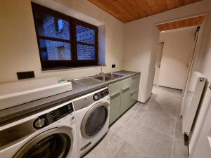 uma cozinha com uma máquina de lavar roupa e um lavatório em De Bogaerd em Lo-Reninge