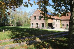 a large brick house with a tree in the foreground at De Bogaerd in Lo-Reninge