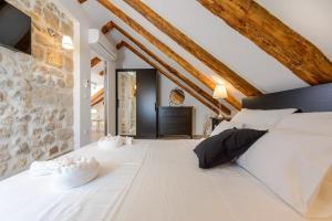 a bedroom with a large white bed with a stone wall at Luxury Deluxe Apartment in Dubrovnik