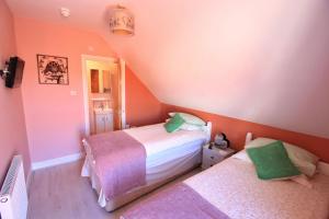two beds in a small room with pink walls at Beaches BandB in Paignton