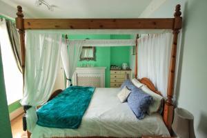 a bedroom with a canopy bed with a blue blanket at Beaches BandB in Paignton
