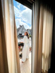 Kobieta stojąca na balkonie patrząca przez okno w obiekcie Hotel Vovó Carolina w mieście Gramado