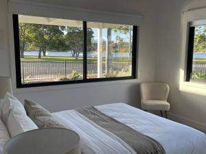 um quarto com uma cama branca e 2 janelas em Skipper’s Lakes Entrance *Waterfront* em Lakes Entrance