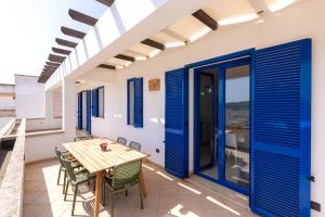 uma sala de jantar com portas azuis e uma mesa e cadeiras em Appartamenti Marinelli - Santa Maria di Leuca em Leuca