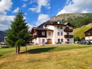 duży dom z drzewem na polu w obiekcie Apartments & Rooms MyHolidayLivigno w Livigno