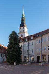 a large building with a tower with a tree in front at Stilvolles Apartment direkt am Marktplatz / Netflix und WiFi in Frankenberg