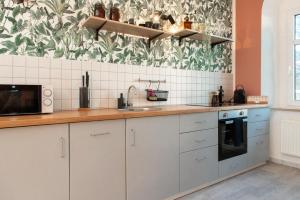 eine Küche mit weißen Schränken und Blumentapete in der Unterkunft Stilvolles Apartment direkt am Markt - Netflix, Nespresso in Frankenberg + 5 Fotos