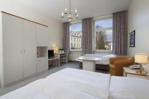 Una habitación de hotel con una cama blanca y un escritorio. en Gästehaus Kaiserhof Lübeck, en Lübeck