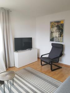 a living room with a chair and a flat screen tv at Appartement Randogne in Crans-Montana