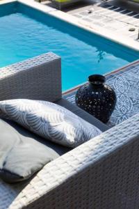 a vase and pillows sitting on a table next to a pool at villa in Agios Nikolaos Anavyssos in Áyios Yeóryios