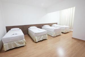 3 łóżka w pokoju z drewnianą podłogą w obiekcie Hotel Perez w mieście Pouso Alegre
