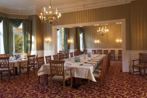 una sala da pranzo con tavoli, sedie e lampadario a braccio di Gästehaus Kaiserhof Lübeck a Lubecca