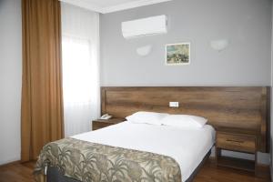 a bedroom with a white bed with a wooden headboard at Cihan Palas in Ankara