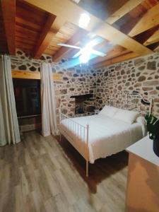 1 dormitorio con cama y pared de piedra en CASA RURAL LA TORRITA, en Acebo