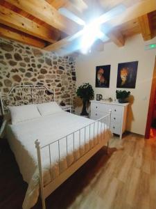 1 dormitorio con cama y pared de piedra en CASA RURAL LA TORRITA, en Acebo