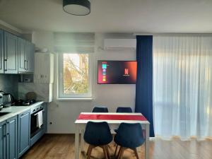 una cocina con mesa y algunas sillas azules en Lily Central Apartment with free parking, en Târgu Mureș