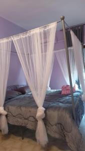 1 dormitorio con cama con dosel y cortinas blancas en I Love Margò, en Torre a Mare