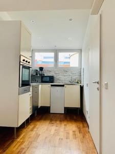 a kitchen with white cabinets and a wooden floor at Aurellia Deluxe Apartments in Vienna