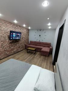 sala de estar con sofá y reloj en la pared en Квартира рядом с ЦОНом,с гостиничным сервисом., en Petropavlovsk