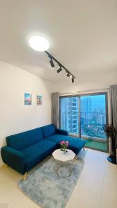 uma sala de estar com um sofá azul e uma mesa em HHomes - Cozy 2 Bedroom & Pool GYM at Masteri Thao Dien D2 em Ho Chi Minh