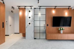 un vestíbulo con TV y una pared con puertas de cristal en Wilczak Apartment with FREE GARAGE Poznań by Renters, en Poznan