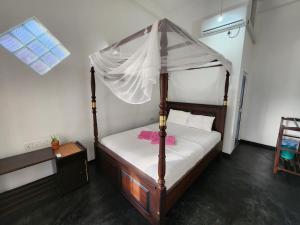 a bedroom with a canopy bed with a pink towel on it at Screwpine Beach Villa in Hiriketiya