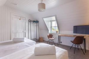 a bedroom with two beds and a desk and a television at Plockton Sea View Apartment in Plockton