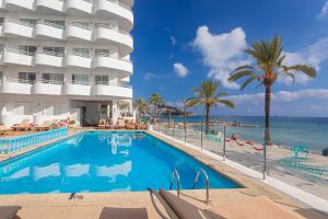 ein Pool neben einem Hotel und dem Meer in der Unterkunft Hotel Ibiza Playa in Ibiza-Stadt