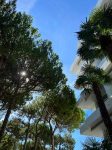 Blick auf ein Gebäude mit Bäumen im Vordergrund in der Unterkunft Hotel Greif in Lignano Sabbiadoro
