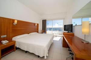 a bedroom with a bed and a desk and a television at Hotel Ibiza Playa in Ibiza Town