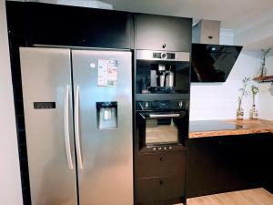 eine Küche mit einem Kühlschrank aus Edelstahl und einem Backofen in der Unterkunft Luxe Family Retreat! Pool, Sauna, Playground, Netflix, Disney Plus in Geraldton