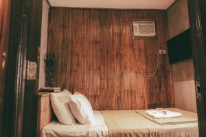 a small room with a bed with a wooden wall at Casitas Stay and Surf in Baler