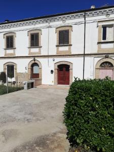 um grande edifício branco com portas vermelhas e uma sebe em casale nonna Elisa relax tra ulivi em San Vito Chietino
