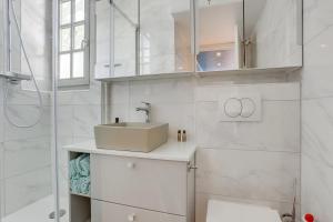 a white bathroom with a sink and a shower at Aux Loges de L'orangerie in Versailles